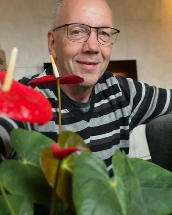 Flemming Tiro Lund smiler bag en plante med røde blomster
